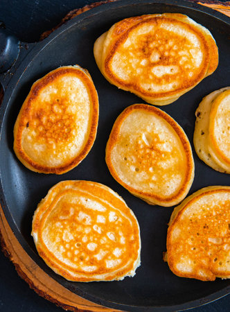 Small pancakes in a pan on a wooden board.の写真素材