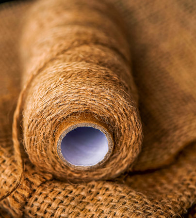 Natural jute twine roll, burlap on black background. Supplies and tools for handmade hobby leisure...