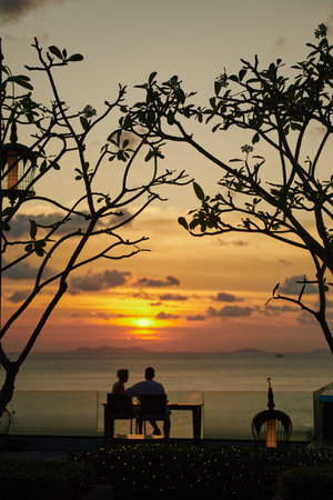 Silhouette of a couple sitting on a table at sunset.の写真素材