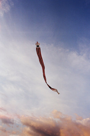 Kite flying in the blue sky with white clouds in the backgroundの写真素材