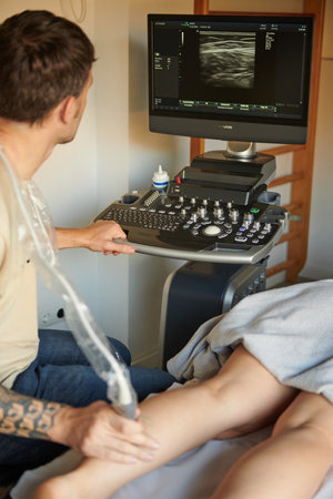 Physiotherapist doing an ultrasound examination of a patient's legの写真素材