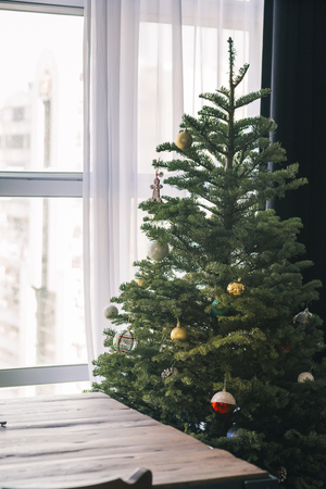 Christmas tree with decoration, detail and colorful ball in daytime in window side,home settingの写真素材