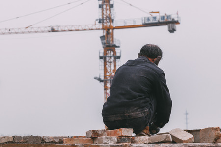 18 Dec,2014 Beijing. a men on a construction site in City with cranes ,takeing Bricks andbuilding...
