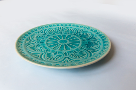 a green round plate with floral and line pattern on white backgroundの写真素材