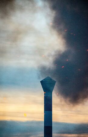 smoke from fire in front of lighthouseの写真素材