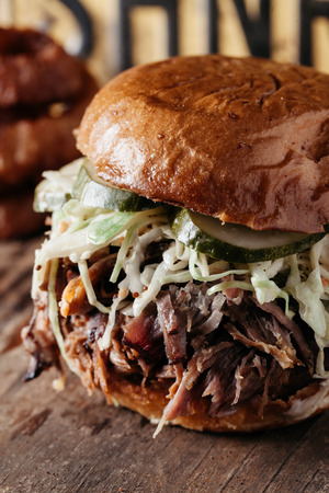 Southern Texas Style BBQ Pulled Pork Sandwich with bleu cheese slaw and dill pickles on rustic backgroundの写真素材