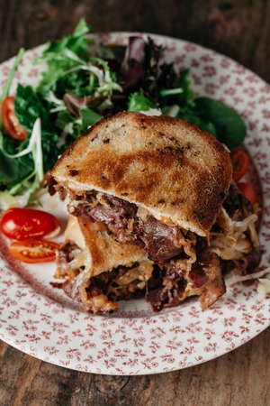 Reuben sandwich on toasted rye bread, made with pastrami meat, Swiss cheese, sauerkraut and dressed with thousand island dressingの写真素材