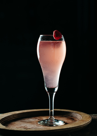 Champagne bubbly alcoholic drink garnished with raspberries on dark backgroundの写真素材