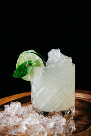 Summer refreshing alcoholic cocktail garnished with cucumbers and mint on black background, verticalの写真素材