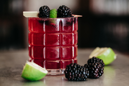 Alcoholic drink garnished with blackberries and limeの写真素材