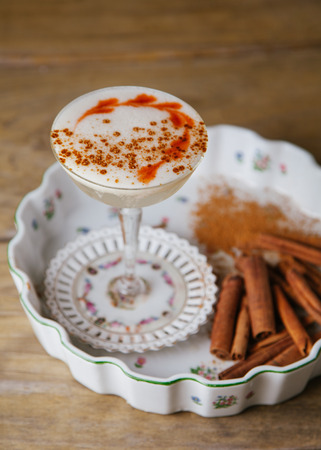 Foamed spicy fall cocktail garnished with cinnamon sticks on rustic backgroundの写真素材