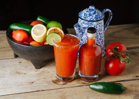 Michelada cocktail next to a bowl of fruit and vegetablesの写真素材