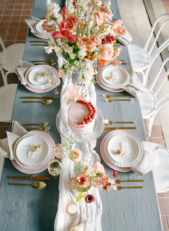 A beautifully decorated dining table features a floral centerpiece and delicate dishes perfect for a celebration. Soft colors complement the elegant atmosphere, ideal for gatherings.の写真素材