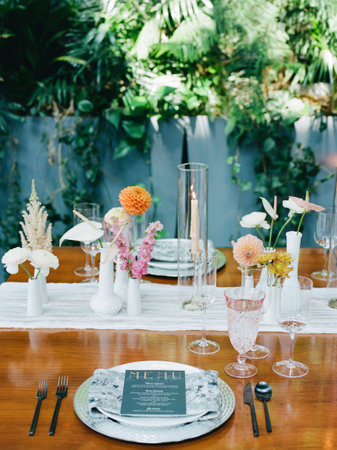 A beautifully arranged table features delicate floral centerpieces in vibrant colors, surrounded by...