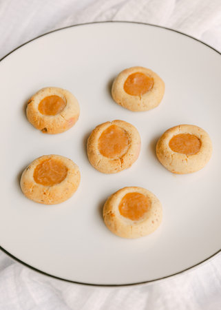 Freshly baked cookies arranged on a white plate, featuring a golden filling. Perfect for sharing at a cozy afternoon gathering with friends and family.の写真素材
