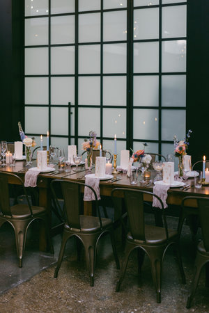 A beautifully arranged dining table featuring a mix of flowers and candles, set in a stylish modern location. The warm light creates an inviting atmosphere for an evening gathering.の写真素材