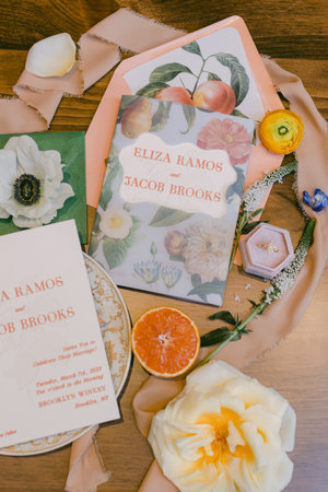 Various wedding invitations are artfully arranged on a wooden table, showcasing floral patterns and decorative accents, creating a charming ambiance.の写真素材
