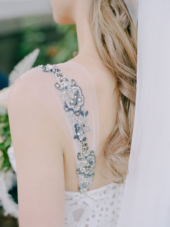 The image captures a bride preparing for her wedding day, highlighting the intricate beading on the back of her elegant gown. Soft hair cascading down enhances the beauty of the moment.の写真素材