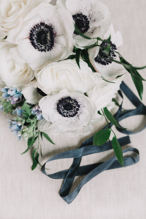 A beautiful arrangement of white flowers with striking dark centers is accented by greenery. Softer ribbons lay elegantly beside the floral display, enhancing the overall aesthetic.の写真素材