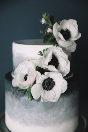 This sophisticated cake features two tiers with a smooth, modern finish. Adorned with delicate white...