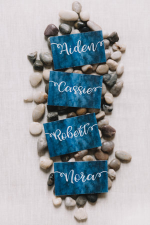 Decorative cards with the names Aiden, Cassie, Robert, and Nora are elegantly placed among smooth,...