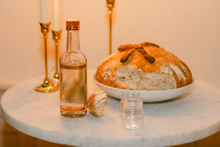 A bottle of wine and freshly baked bread are beautifully arranged on a marble table illuminated by...