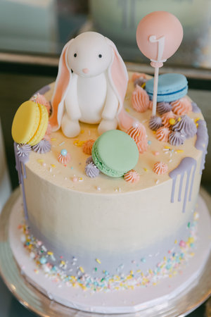 A festive birthday cake features a bunny decoration and vibrant macarons, perfect for a joyful celebration.の写真素材