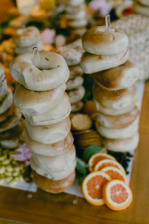 A visually appealing arrangement of bagels stacked artistically, accompanied by fresh orange slices at a gathering.の写真素材
