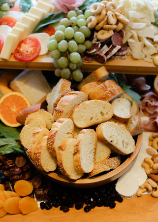 A variety of cheeses, cured meats, fresh fruits, and sliced bread are beautifully arranged on a...