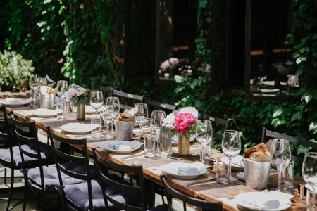 An inviting outdoor table is beautifully arranged for dining, adorned with flowers and surrounded by...