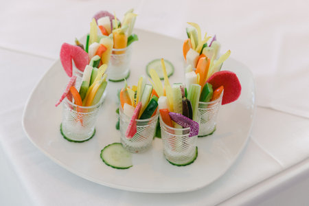Freshly prepared vegetable sticks arranged in small elegant cups at a catering event, showcasing vibrant colors.の写真素材