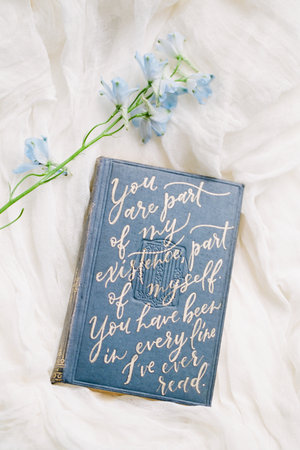 Quote filled book lies on soft fabric with light blue flowers, creating a tranquil and inspiring atmosphere.の写真素材