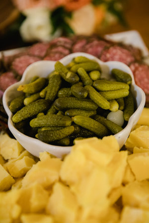 A variety of pickles is presented in a bowl surrounded by fresh cheese, creating a delightful platter for guests.の写真素材