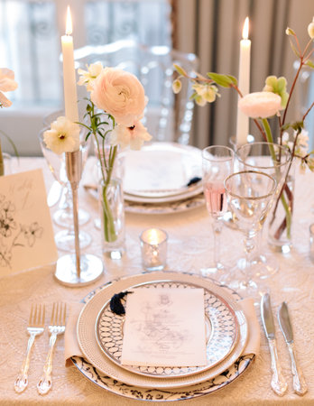 Beautifully arranged dining table features flowers, candles, and fine dinnerware, creating a warm...