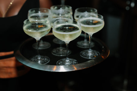A tray of sparkling cocktails is presented at a lively event, showcasing a celebratory atmosphere...