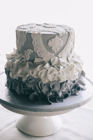 A stunning gray and white wedding cake with lace and ruffles, perfect for celebrations.の写真素材