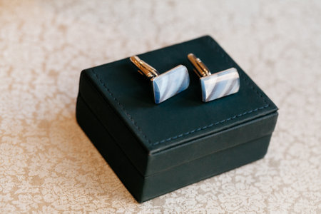 Exquisite cufflinks with blue accents are displayed in a black box, adding a touch of sophistication to the setting.の写真素材