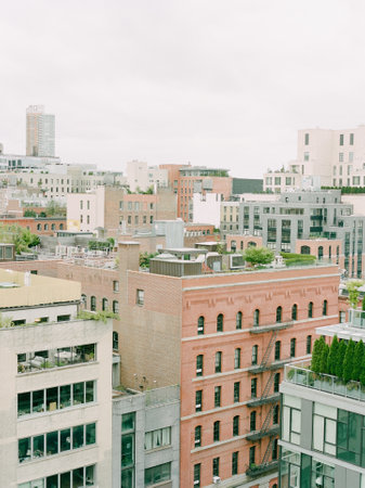 Overlooking a vibrant urban landscape filled with buildings, greenery, and a cloudy sky, showcasing city life.の写真素材