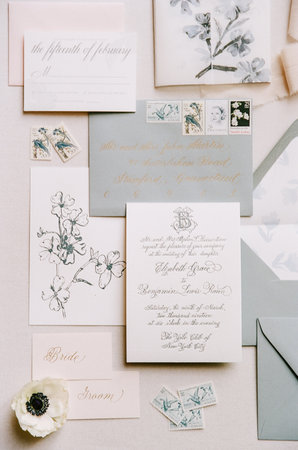 Floral-themed wedding invitation suite with vintage stamps displayed beautifully on a light beige...