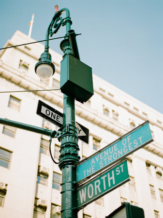 Street signs for Worth St. and Avenue of the Strongest stand out against a sunny architectural backdrop.の写真素材