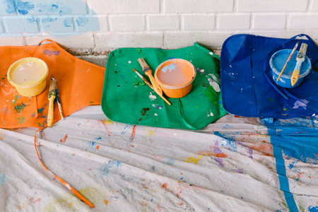 Bright paint containers and brushes are arranged on the floor, capturing the essence of an artistic...