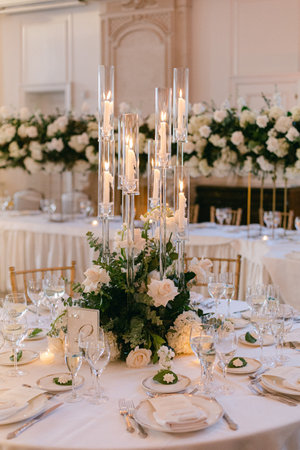 Floral arrangements and candles create a romantic atmosphere for an upscale dining experience at a celebratory event.の写真素材