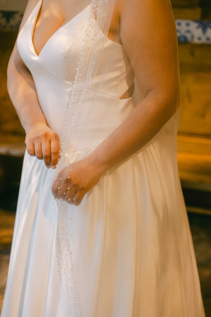 A bride prepares for her special day in a charming location, adjusting her beautiful gown with care and excitement.の写真素材