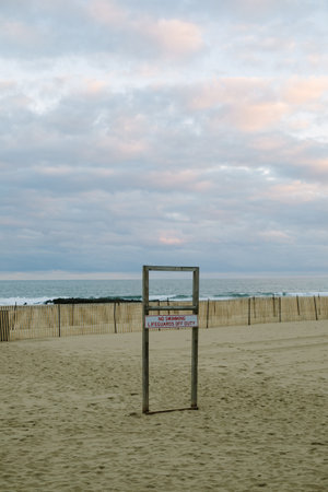 A lifeguard station is positioned on a sandy beach as evening approaches, with gentle waves lapping the shore.の写真素材