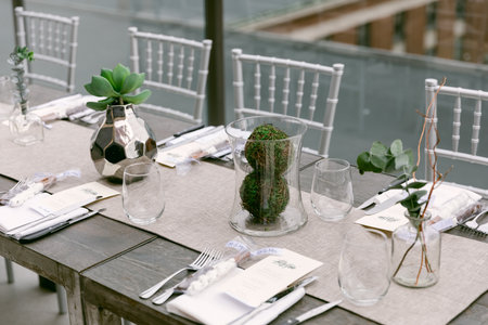 A stylish dining arrangement featuring greenery and glass accents, perfect for an upscale event on a rooftop.の写真素材