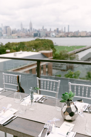 A beautifully arranged dining table awaits guests, showcasing a stunning city skyline against a cloudy backdrop.の写真素材