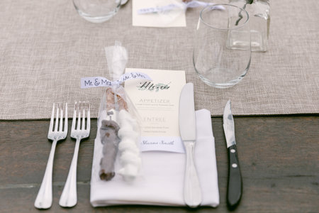 Decorative table features utensils, place cards, and a menu for guests during a wedding reception...