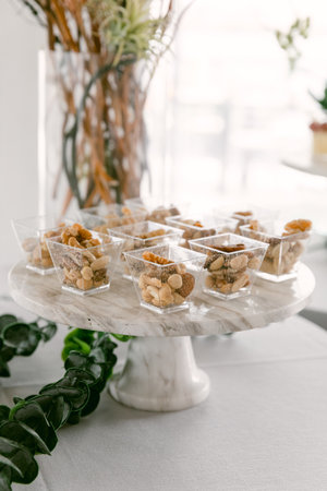 Delicious dessert cups filled with nuts and toppings are arranged on a stylish marble stand at an...