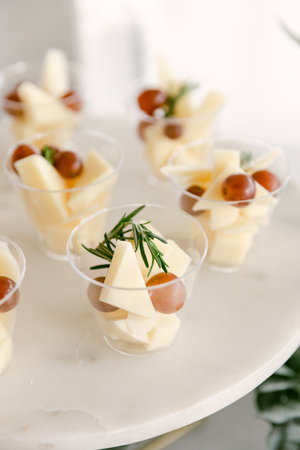 Delicious cheese and grape appetizer cups presented on a marble platter during an upscale gathering.の写真素材