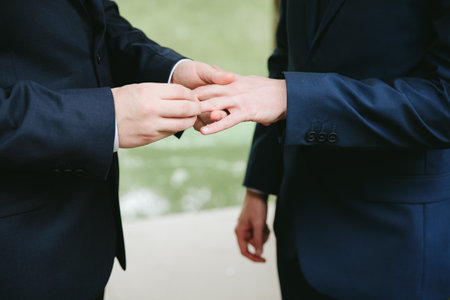 Two individuals are exchanging wedding rings in a peaceful outdoor setting, showcasing their love and commitment.の写真素材